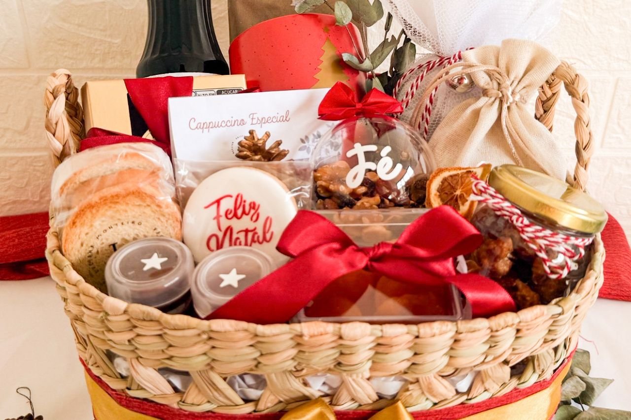 Cesta de Natal artesanal com biscoitos, cappuccino especial, castanhas, doces caseiros, laços vermelhos e decoração temática.