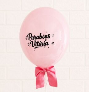 Balão rosa redondo personalizado com a frase Parabéns Vitória em letras pretas e laço de cetim. Item adicional para personalizar cesta de café da manhã